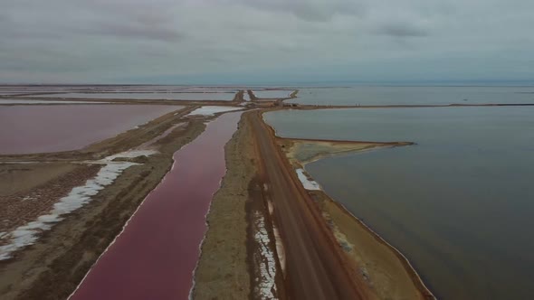 Drone shot of a salt mine in Namibia - drone is following a transportation road surrounded by red la