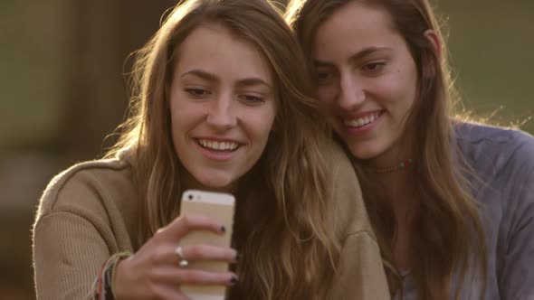 Teenage girls posing of photos they are taking with smartphone