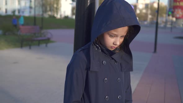 Portrait of a Teenage Girl with a Burn on the Street with a Hood