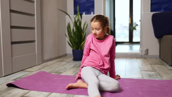 Little Girl Doing Stretching Exercises Practicing Yoga on Fitness Mat at Home