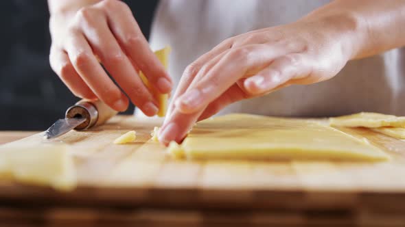 Woman slicing dough on chopping board