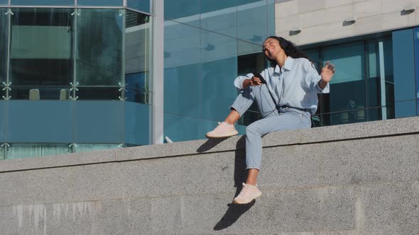 Happy Carefree Young Brunette Girl Woman Lady Sitting on Street in the City Urban Buildings