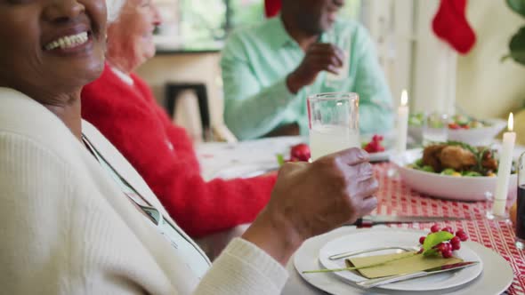 Happy african american senior woman celebrating meal with friends at christmas time