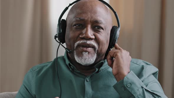 Senior Dominican 60s Freelancer Businessman in Digital Earphones Talking to Camera Online Using