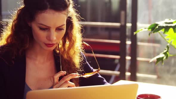 Female executive using laptop while having coffee