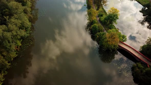 Public park romantic small walking bridge over pond located at green quiet scenery trees hanging ove