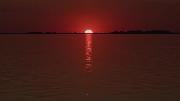 Sun Sitting Low Over the Horizon and Reflecting in a River on a Red Sunset