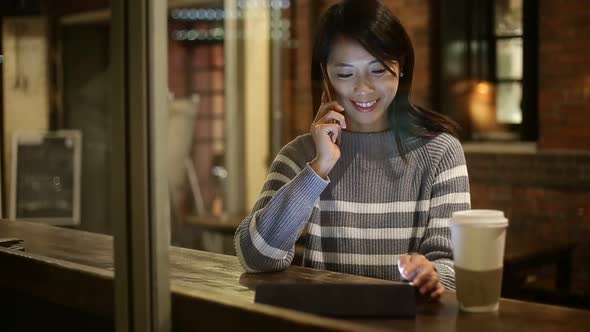 Woman using tablet pc at coffee shop at night