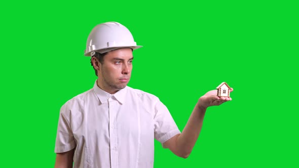 Young Male Engineer Standing and Showing Hand Palm with Small Model of House on Green Screen