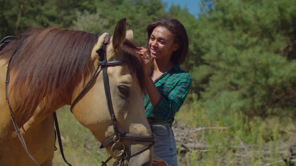 Smiling Black Woman Caressing Horse Head Outdoors