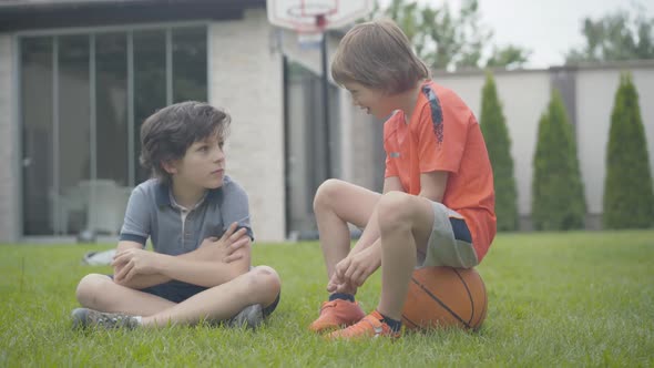 Excited Little Boy Sitting on Ball and Talking with Friend. Portrait of Two Happy Caucasian Children