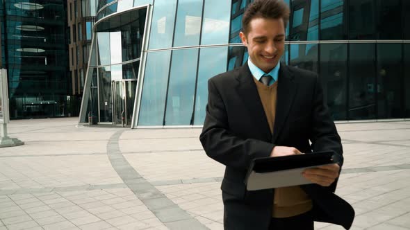 Businessman Using Electronic Tablet Outside a Building