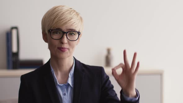 Close Up Portrait of Optimistic Middle Aged Businesswoman in Glasses Smiling to Camera and Gesturing