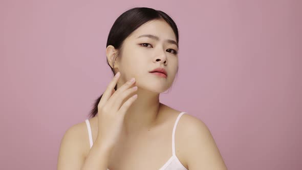 Close up face of young Asian woman worry about face skin problem on pink background.