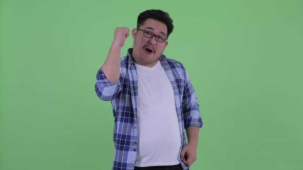 Happy Young Overweight Asian Hipster Man Giving Thumbs Up and Looking Excited