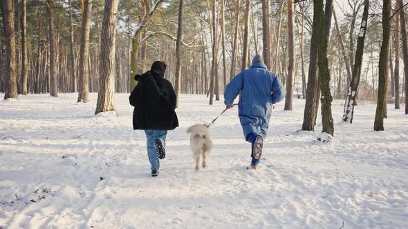 Young Happy Family Runs Along the Path with the Dog