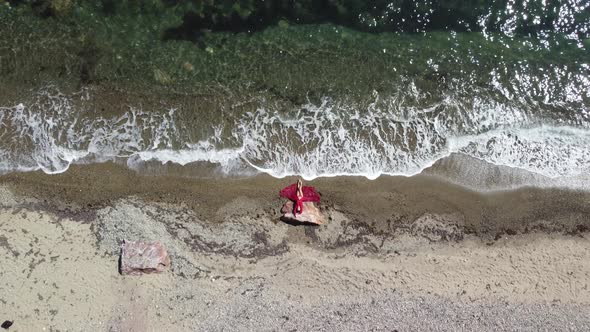 Top Aerial View on a Young Sensual Blonde Woman in Red Bikini Lying on the Rock Near Water at Sea