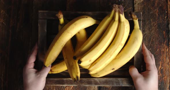 Male Hand Put a Wooden Tray with Fresh Bananas