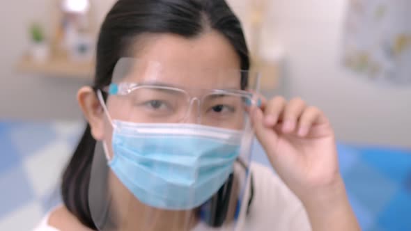 Portrait of an Asia young female who is wearing a face shield with mask rounded around her face from