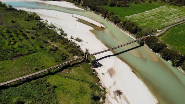 Aerial Top Down View of Sheep and Rams Crossing the Mountainous River on the Bridge with Shepherd in