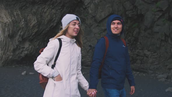 Young Couple Holding Hands Walking Down Black Sand Beach in Iceland Slow Motion