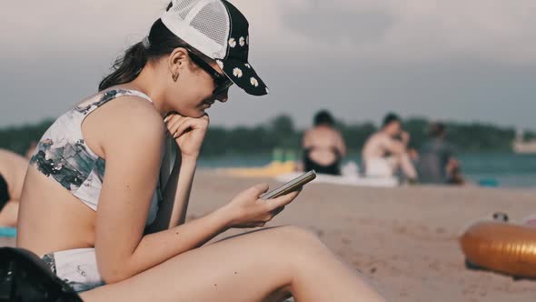 Young Woman Uses a Smartphone on the Beach