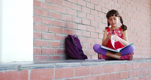 School girl sitting in corridor and doing homework at school