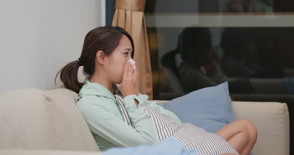 Sick woman sneeze and sit on sofa at home