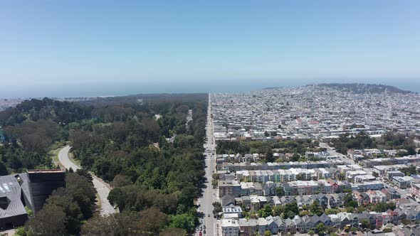 Wide aerial shot flying over a street equally dividing Golden Gate Park and city suburbs in San Fran