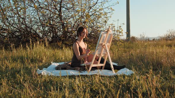 Happy girl painting outdoors in a field
