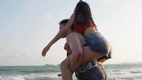 Asian young man and woman having fun, playing on the beach together enjoy holiday honeymoon trip