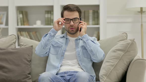 Young Man Talking on Smartphone at Home