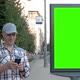 Middle-aged Man Stands on City Street Next To Billboard and Clicks on Smartphone - VideoHive Item for Sale