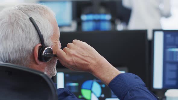 Man wearing headset talking while sitting on his desk at office