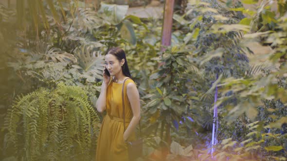 Young Asian Woman Having Phone Talk in Indoor Garden