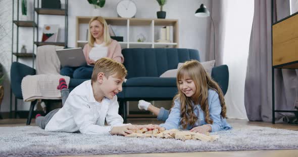 Brother and Sister Lying on the Floor and Talking Before Playing with Wooden Blocks