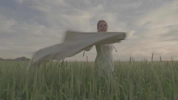 A Young Beautiful Girl in an Ethnic Dress is Spinning in a Green Field of Wheat