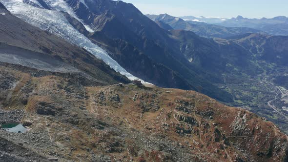 Aerial of distant buildings on a high mountain ledge overlooking a beautiful valley