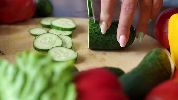 Closeup of Cook Cutting Fresh Cucumber on Wooden Chopping Board