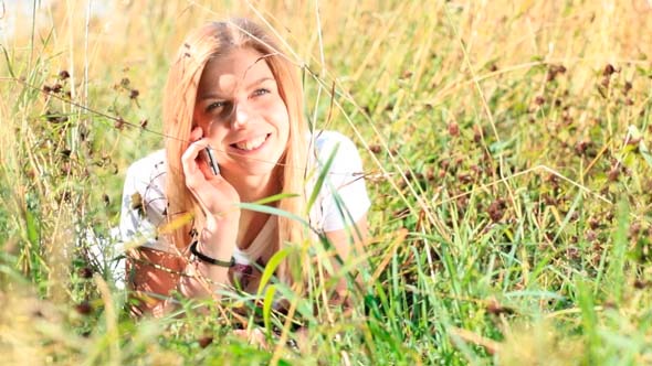 Young Girl Talking on the Phone in the Grass