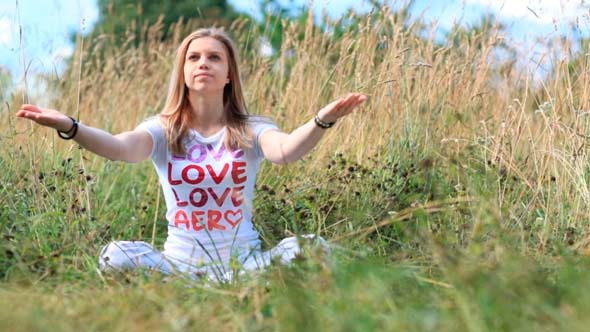 Young Girl in White Meditating in the City Park