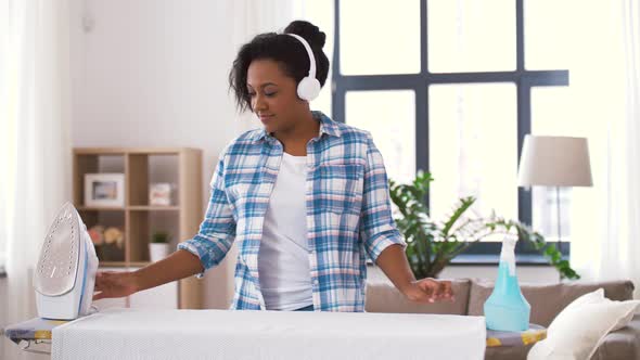 African American Woman Ironing Bed Linen at Home