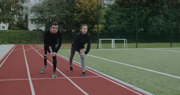 Disabled Man and Young Woman Taking Position on Marks and Start Running