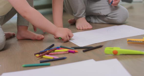 Close Up o Hands and Feet of a Little Boy and a Little Girl Who are Drawing with Pencils on the