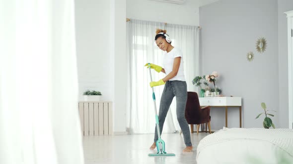 Pretty Mixed Race Girl Cheerful Maid Is Cleaning Floor in Beautiful Flat with Plastic Mop and