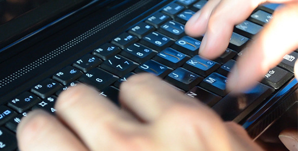 Man Typing Fast on a Black Laptop