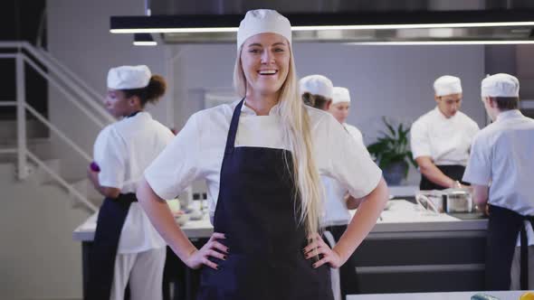 Caucasian female cook working in a restaurant kitchen looking at camera and smiling