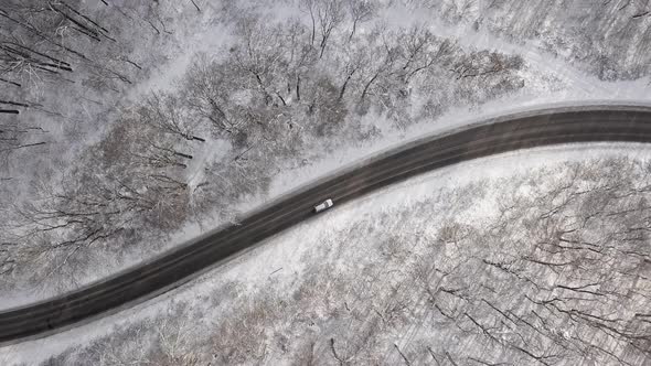 Overhead View of Car Driving Through Winter Forest