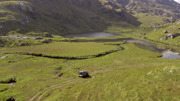 ATV All Terrain Vehicle Driving Over Rugged Land Towards A Remote Lake