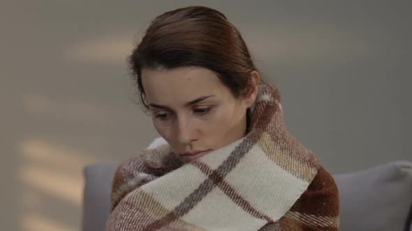 Depressed Young Woman Sitting on Couch, Covered With Plaid, Terminal Illness